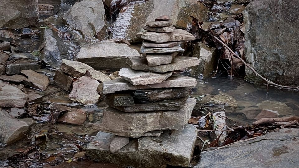 Balanced stone cairn in natural setting, symbolizing the intentional building of new life systems.