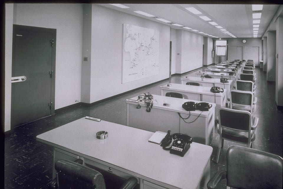 Empty office corridor with rows of desks and vintage phones, capturing the ghostly feeling of a transitioning workplace.